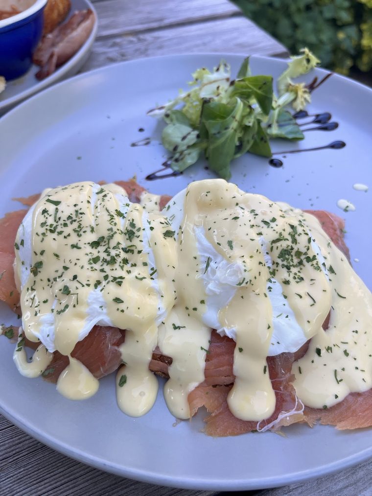 Close crop of eggs Benedict under hollandaise with a salad garnish